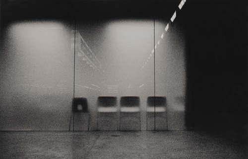 Plastic chairs seen through a window.